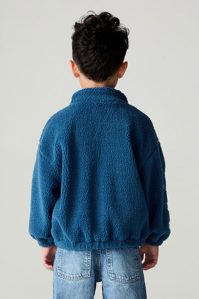 Back view of a boy wearing the Chaser White Bolts Boys Jacket and jeans on a neutral background