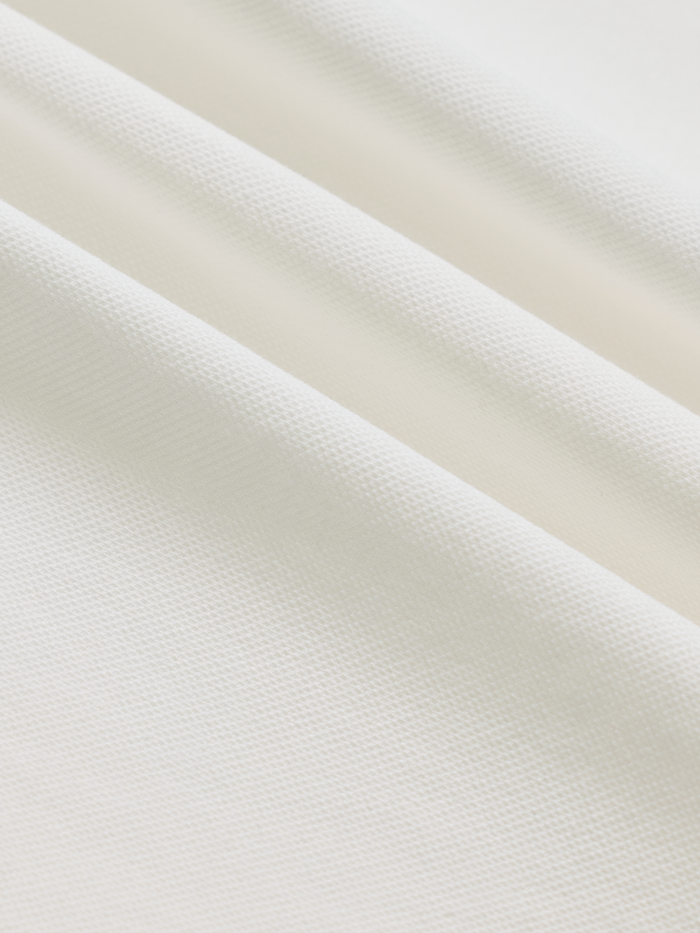 Close-up of white cotton pique fabric texture with soft folds
