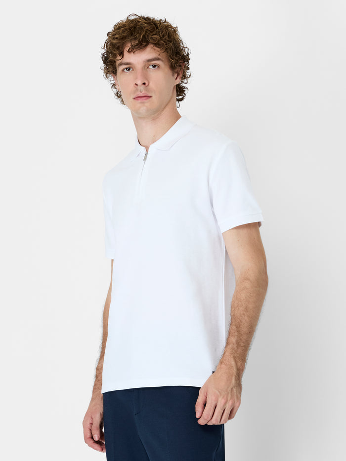 A man wearing a white cotton Polo shirt with short sleeves, a branded metal half zip and a regular fit.