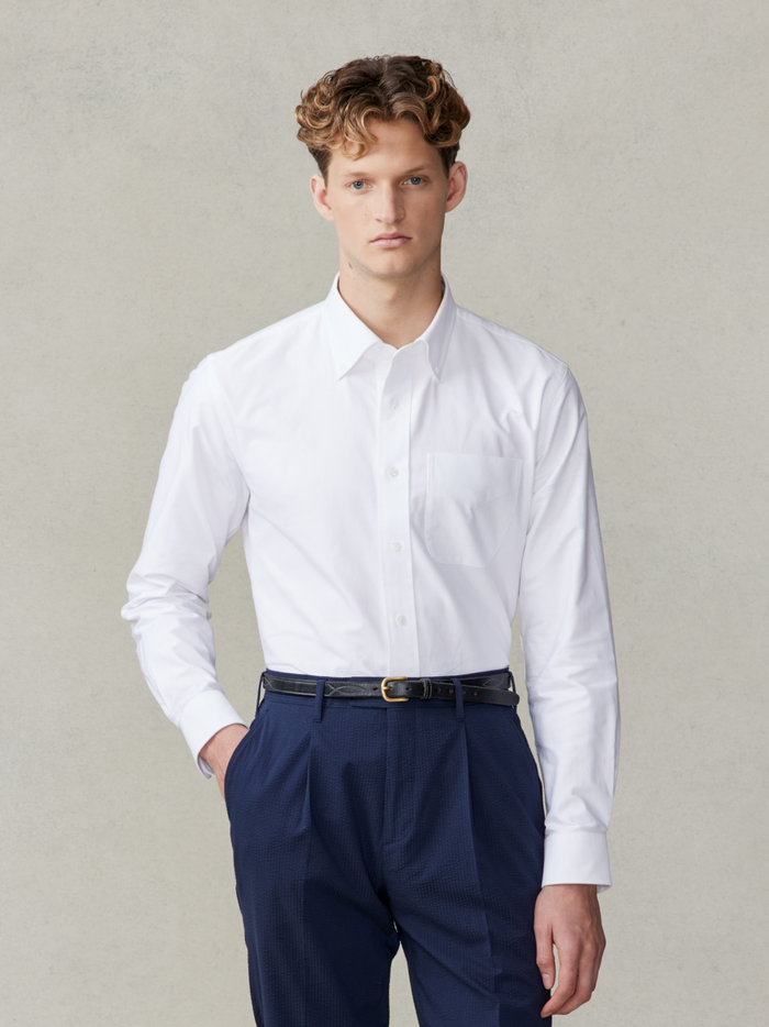 Man in white oxford shirt and navy trousers, front view, waist-up