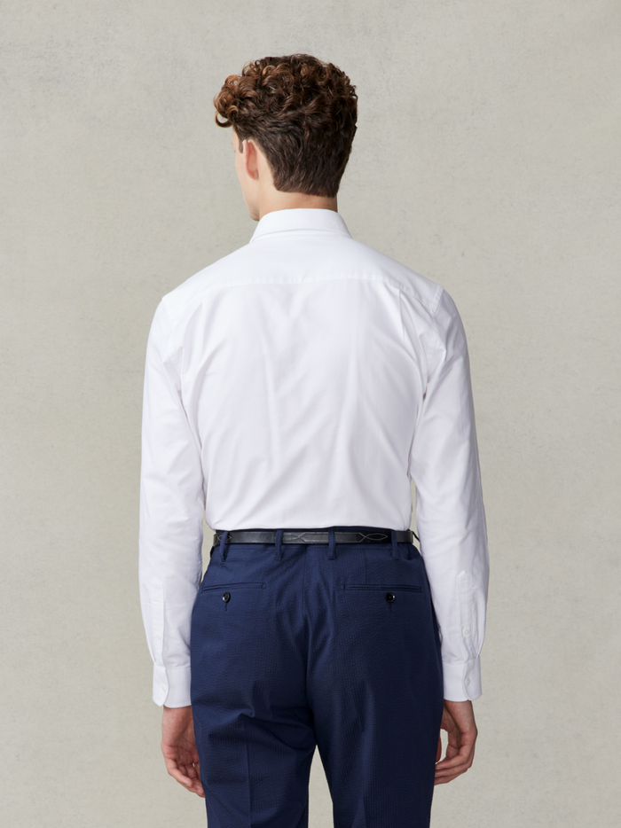 Back view of man in white oxford shirt and navy trousers, waist-up