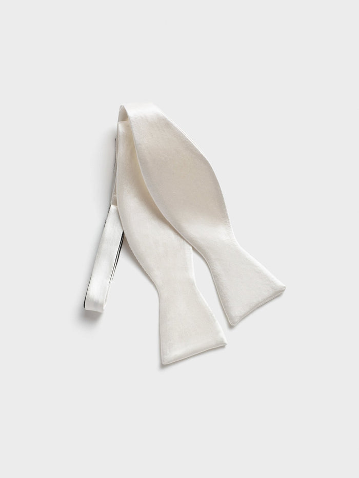 White satin bow tie, untied and twisted, back strap and clasp visible.