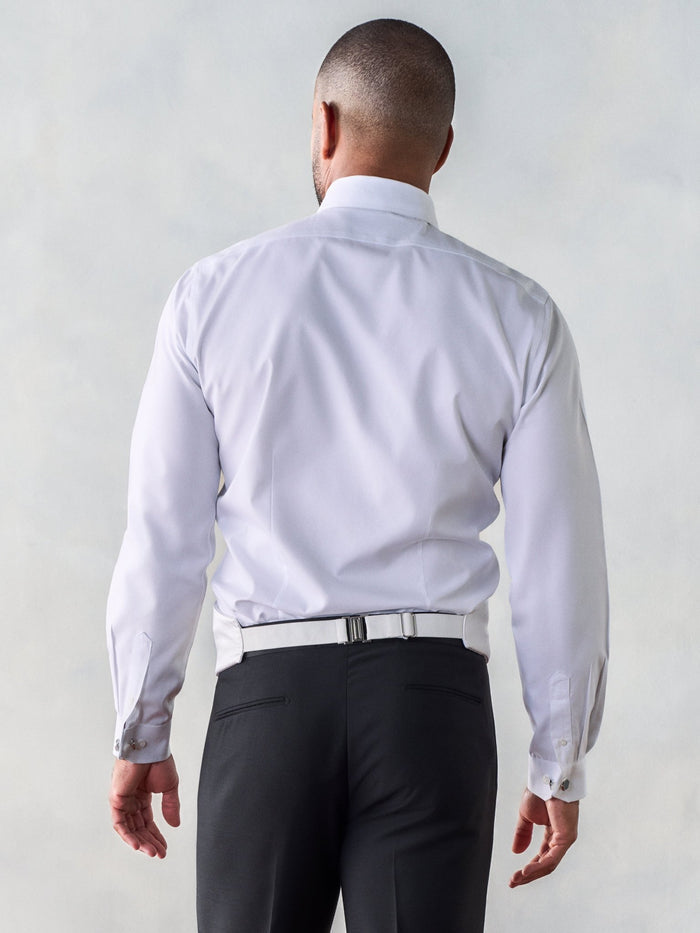 Back view of a man in a white shirt, cummerbund buckle strap visible at the waist.