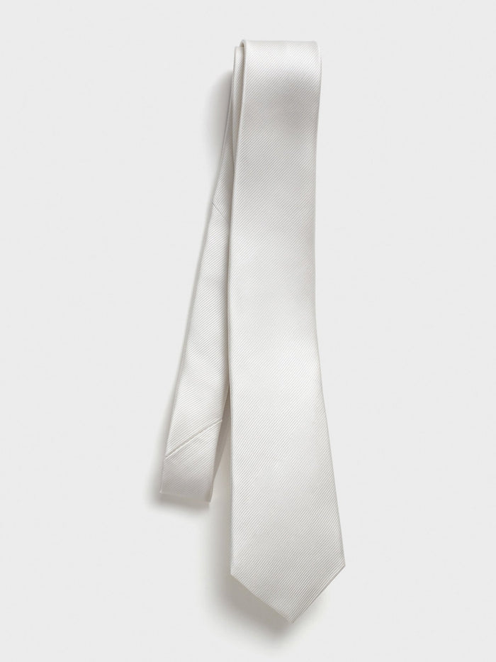 White silk tie draped loosely on light grey background