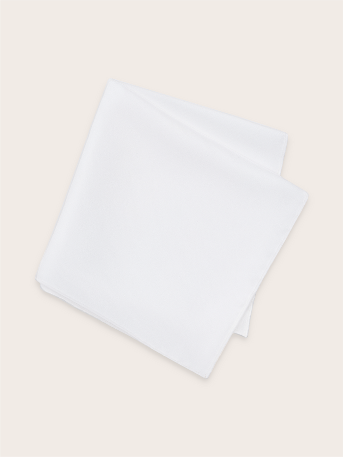A white silk pocket square folded against a light background