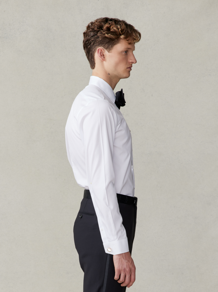 Man in white stretch cotton dress shirt and black bow tie, side profile view, waist-up