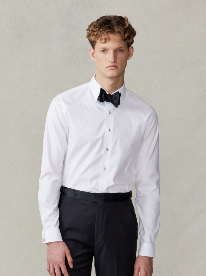 Man in white stretch cotton dress shirt and black bow tie, front view, waist-up