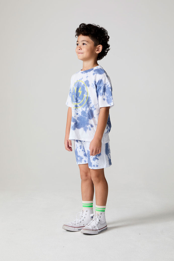 A side angle front view of a boy wearing the Chaser Wide Leg Mistel Tie Dye Shorts on a neutral background
