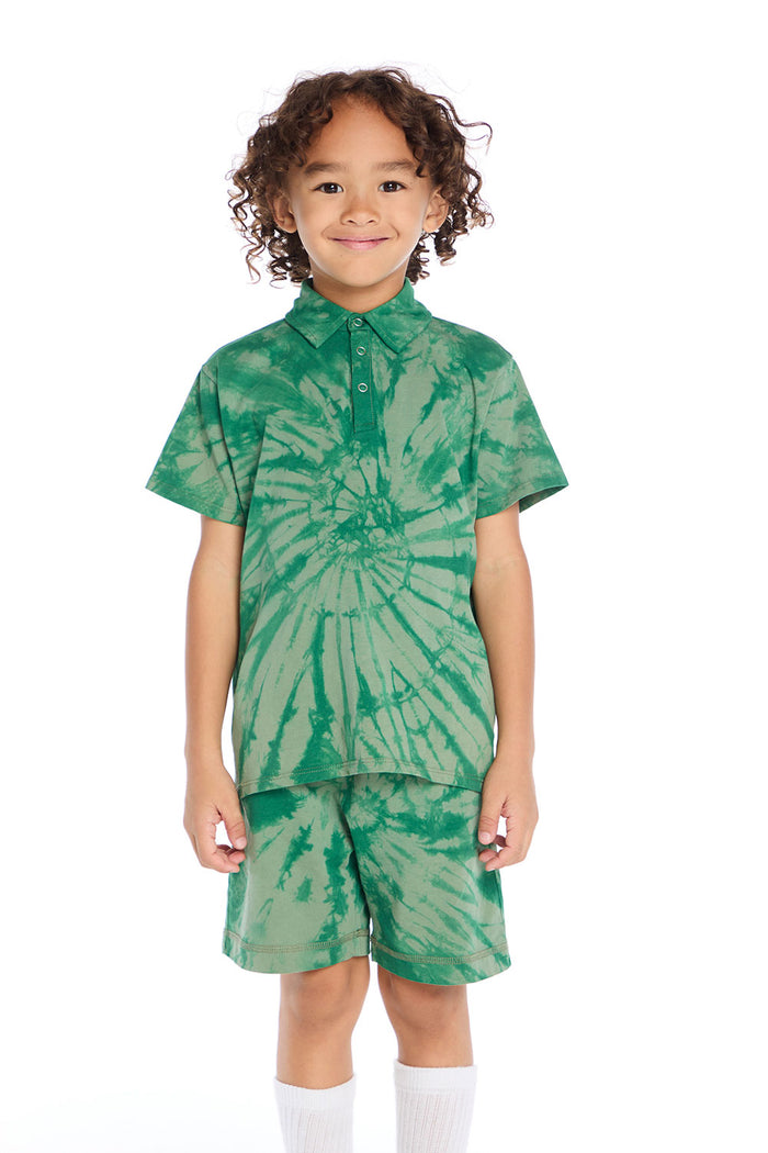 Front view of boy wearing the Chaser Kids Wild Green Tie Dye Polo Shirt featuring a button placket and spiral tie dye pattern, paired with matching Wild Green Tie Dye Cozy Beach Shorts on a white background