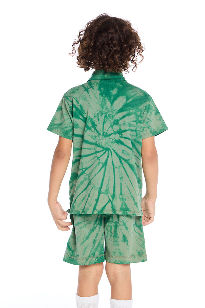 Back view of boy wearing the Chaser Kids Wild Green Tie Dye Polo Shirt featuring a large spiral tie dye pattern across the back, paired with matching shorts on a white background