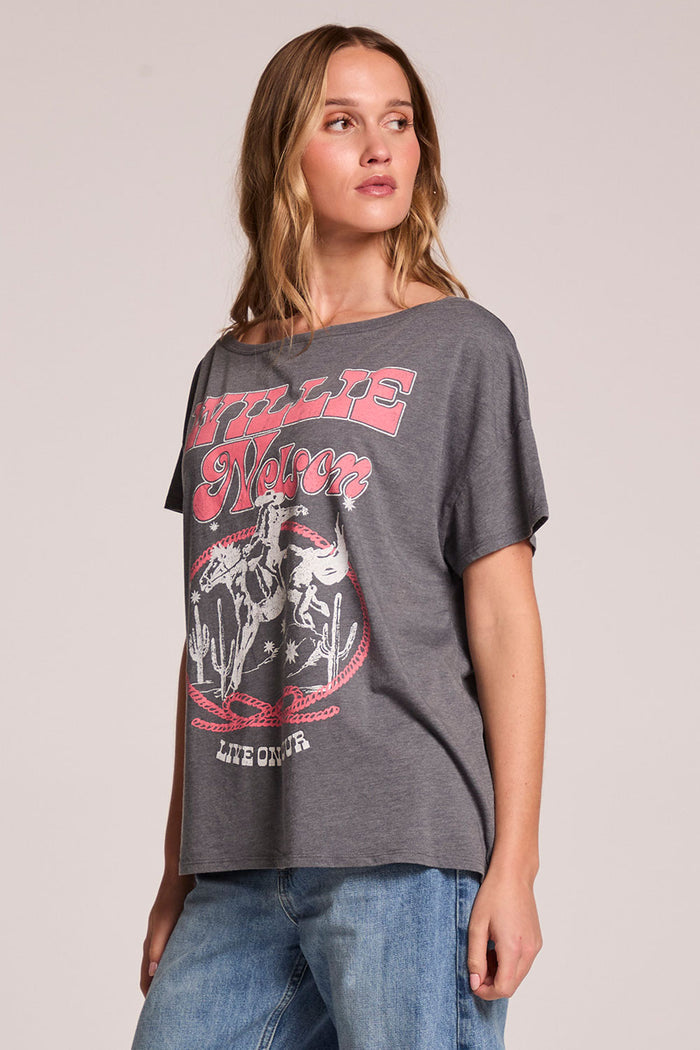 Side angle view of a woman wearing the Chaser  Willie Nelson 77 Tour Tee on a neutral background with arms at her sides