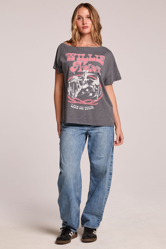 Full body front view of a woman wearing the Chaser  Willie Nelson 77 Tour Tee and sneakers on a neutral background
