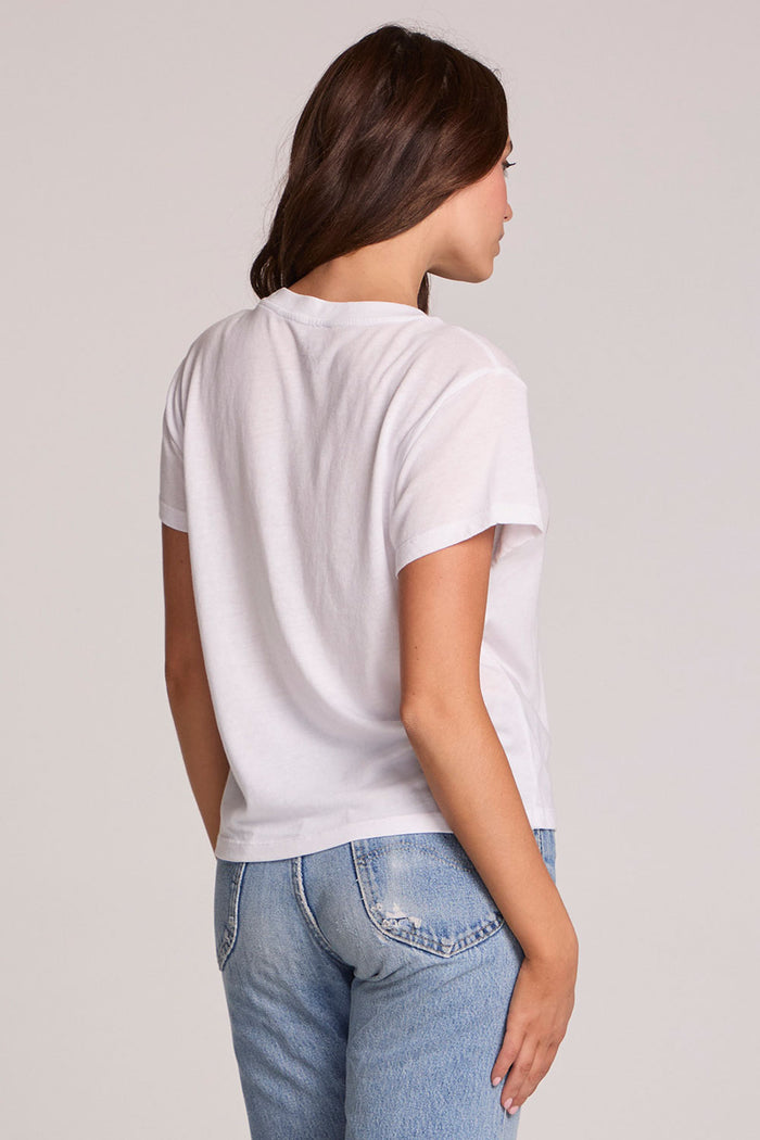 Back view of a woman wearing the Chaser Willie Nelson Fan Club Tee on a neutral background with arms at sides and blue jeans