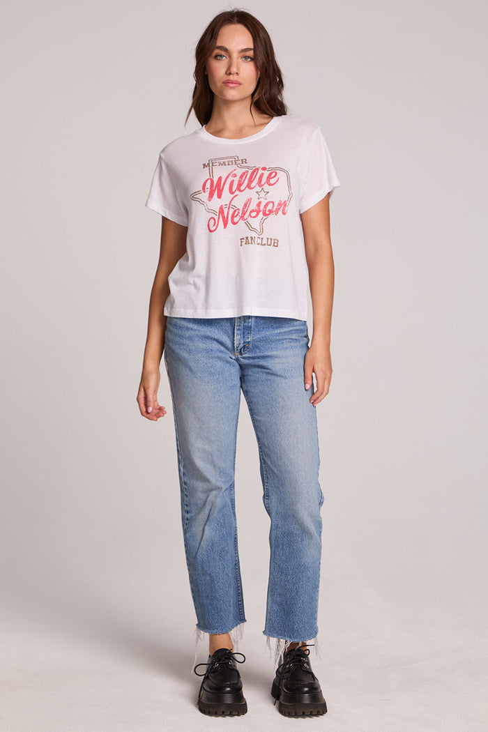 Full body front view of a woman wearing the Chaser Willie Nelson Fan Club Tee on a neutral background with and blue jeans