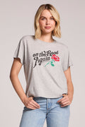 Back view of a woman wearing the Chaser Willie Nelson On The Road Again Tee on a neutral background with her hands in her pockets