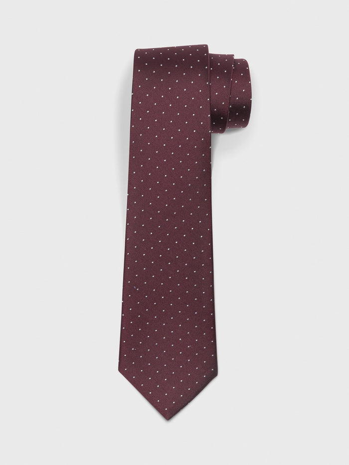 Wine silk necktie with white pin dots, rolled at the top on a white background