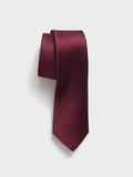 Wine silk necktie, rolled, on light grey background
