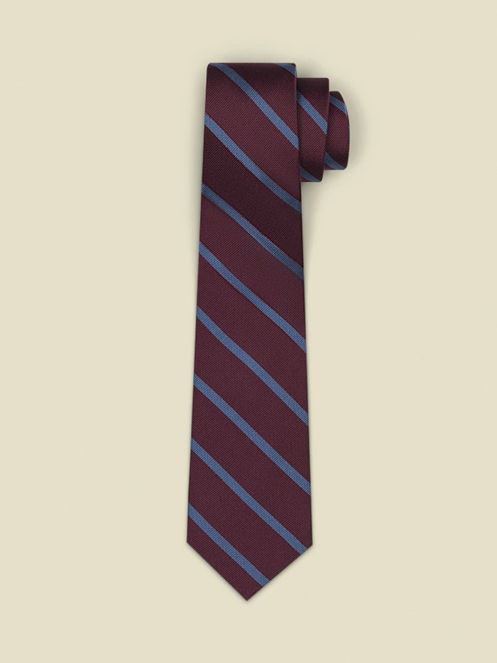 Wine-colored necktie with diagonal blue stripes, rolled on a cream background.