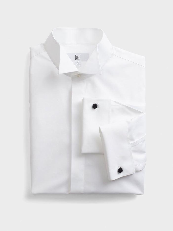 White wing-collar fly-front dress shirt, flat lay, folded with cufflinks visible