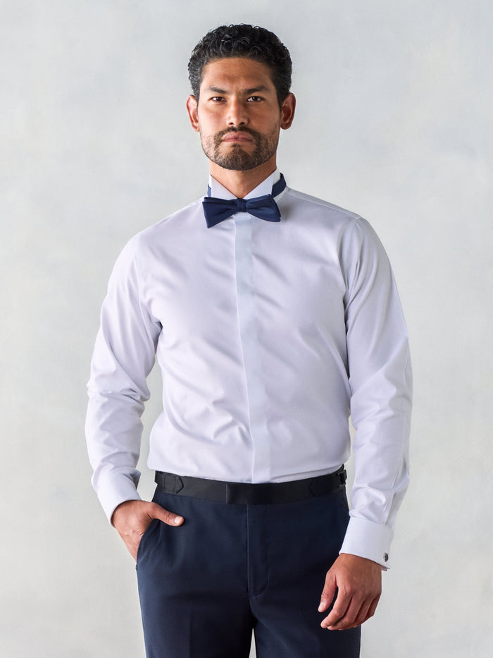 Man in white wing-collar dress shirt and navy bow tie, front view, waist-up