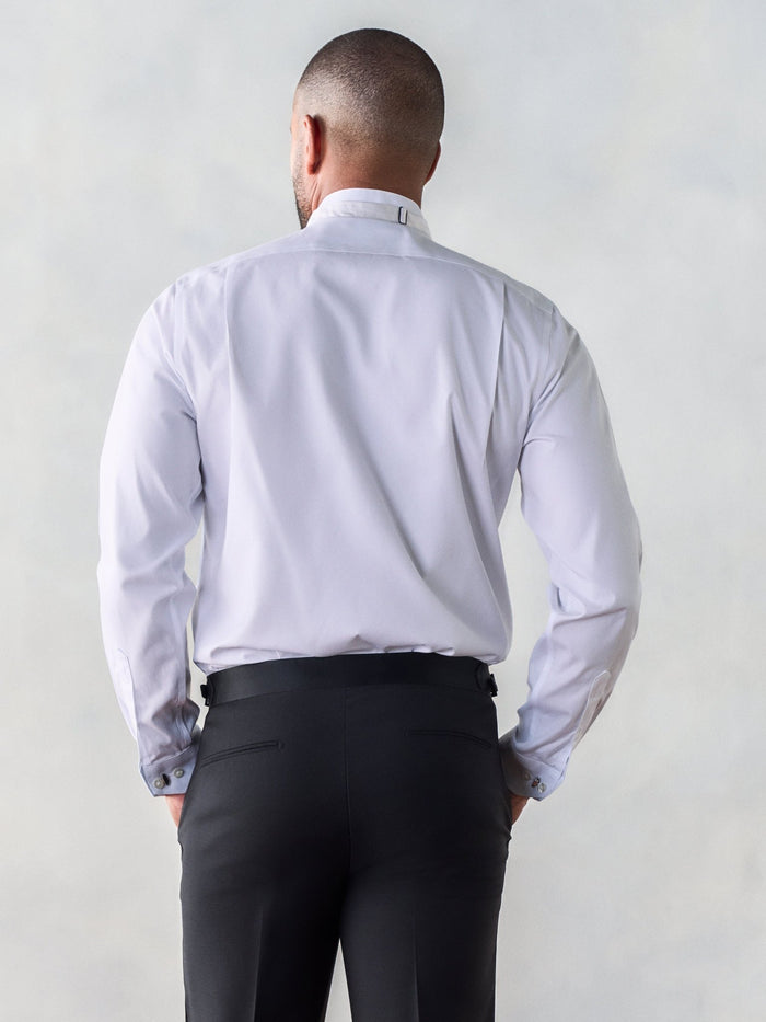Man in white wing-tip tuxedo shirt and black pants, back view