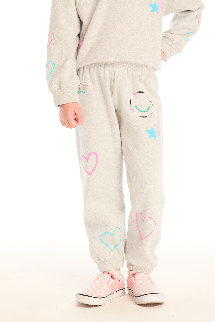 Girl wearing Chaser’s light gray Winter Love Pants with colorful designs on a white background