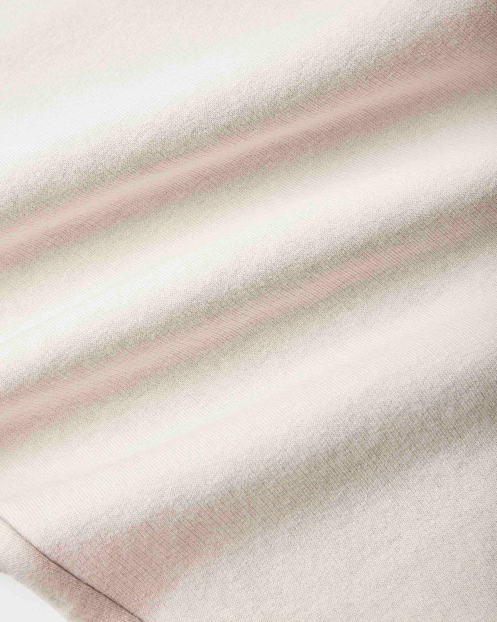 A close-up of a soft, textured fabric with a fine knit pattern, featuring horizontal stripes in cream, light beige, and a muted dusty pink.