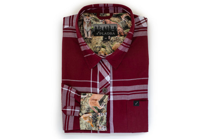 The Women's Breeze Shirt in Merlot Red is a folded, organic cotton plaid button-up with wildlife-themed fabric—wolves and bears—inside the collar and cuffs. The Pladra brand label is sewn inside the collar.