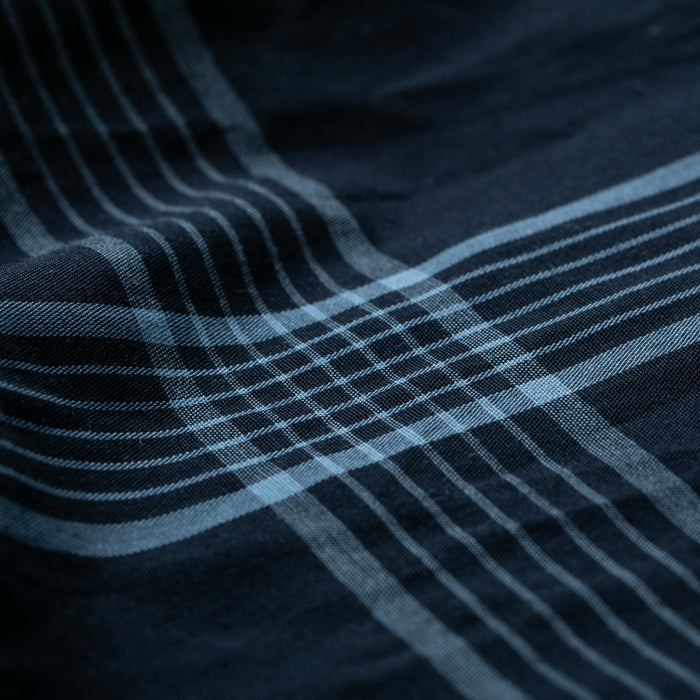 Close-up of the Women's Breeze Shirt in Ocean Blue—a tencel cotton shirt with a dark blue plaid pattern, subtle wrinkles for texture, and a soft, breathable feel.