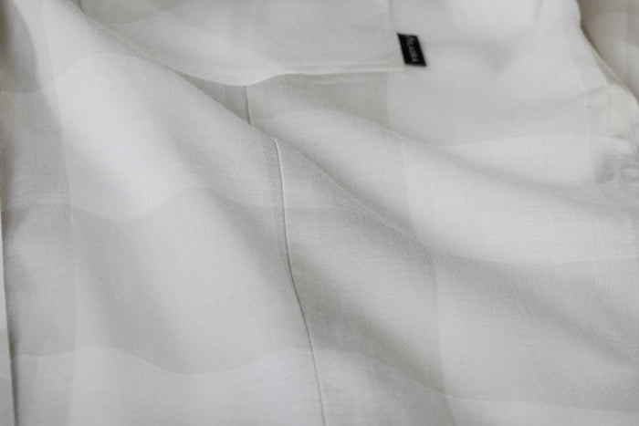 Close-up of Pladra Women's Breeze Shirt in Whisper Grey, featuring white checks and a black label near the top edge.