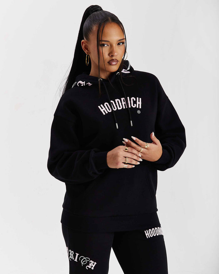 Person wearing a black 'Hoodrich' hoodie and pants on a white background