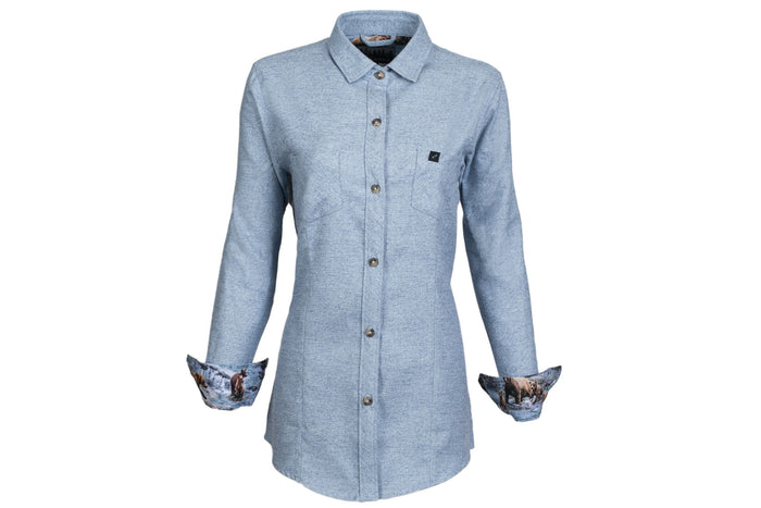The Women's Cascade Flannel Shirt in Dusty Blue is made from heavy Portuguese brushed cotton with long sleeves, a single chest pocket, and turned-up cuffs revealing nature-printed fabric. Shown on a white background.