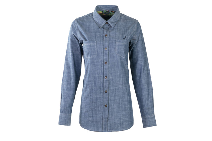 The Women's Cascade Shirt in Indigo Blue Chambray features long sleeves, a collared neckline with colorful lining, two chest pockets, button closures, and is crafted from sustainable cotton for comfort.