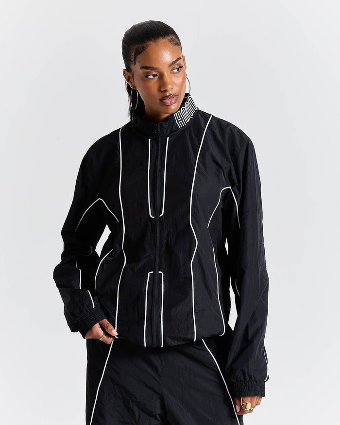 Person wearing a black outfit with white piping on a plain background