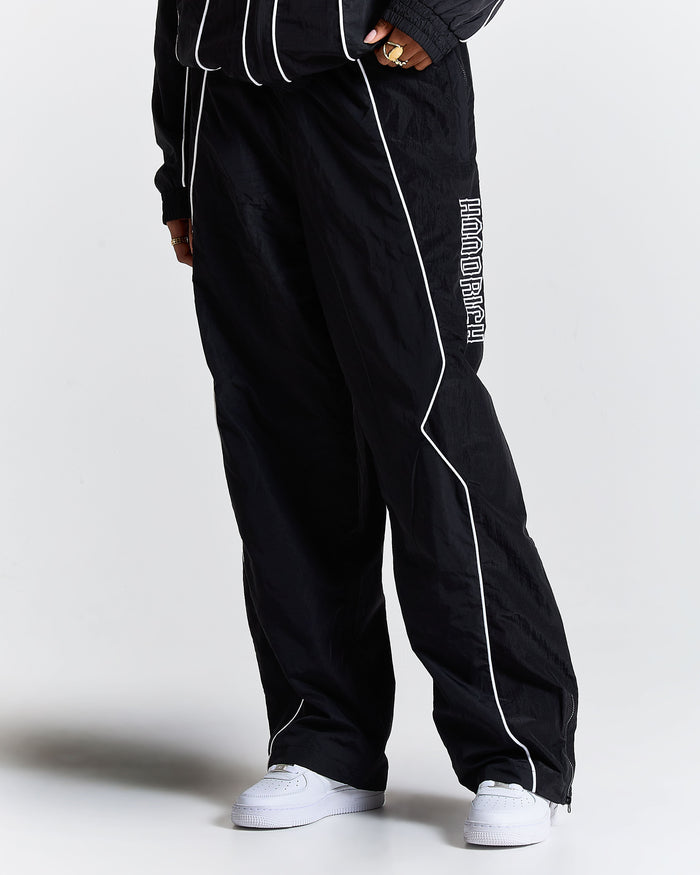 Black track pants with white piping and text on a plain background