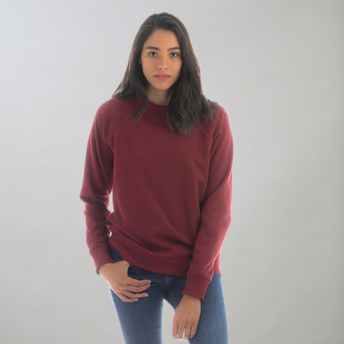 Women's Crew Neck Sweatshirt in Pomegranate Red, worn with blue jeans.