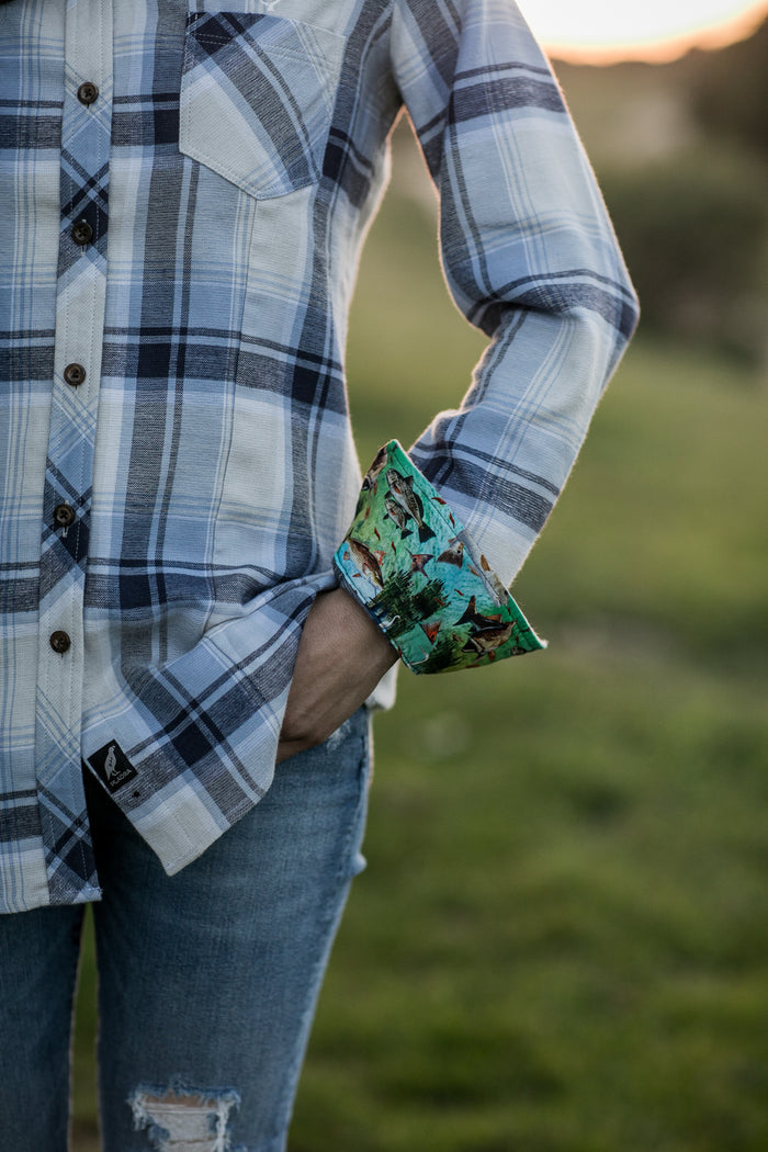 Woman in Pladra Women's Every Day Double Weave Shirt - Birch White, jeans, cuff showing colorful fabric, on grass.
