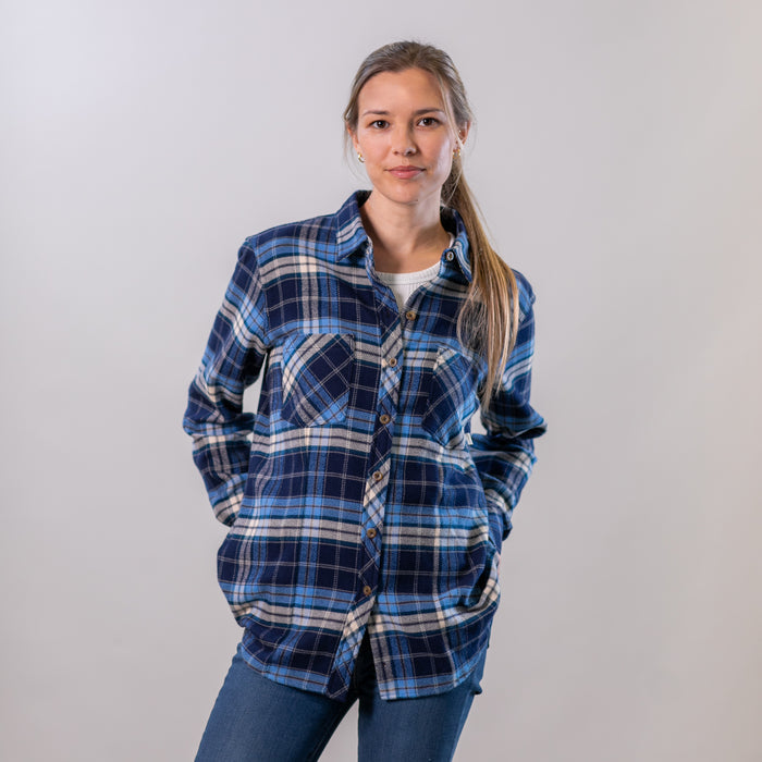 A woman wears the Pladra Women's Every Day Elite Flannel Shirt in Bighorn Blue and jeans, facing the camera.