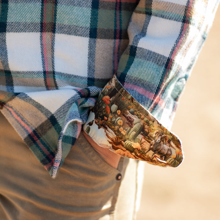 A person in khaki pants and a Pladra Women's Every Day Elite Flannel Shirt—Coyote Tan with desert landscape cuffs.