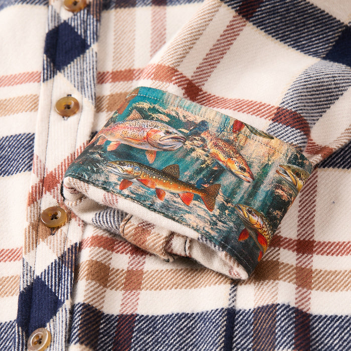 A close-up of the Women's Every Day Elite Flannel Shirt–Whitefish Tan shows cream, blue, and brown premium cotton, with a folded cuff revealing a colorful lining of trout swimming underwater.