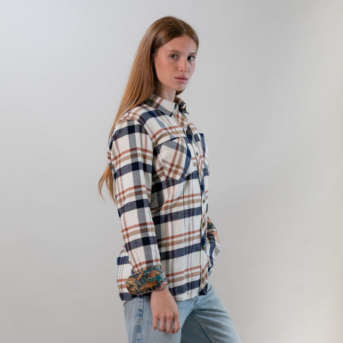A woman wears the Pladra Women's Every Day Elite Flannel Shirt in Whitefish Tan with jeans, posing sideways.