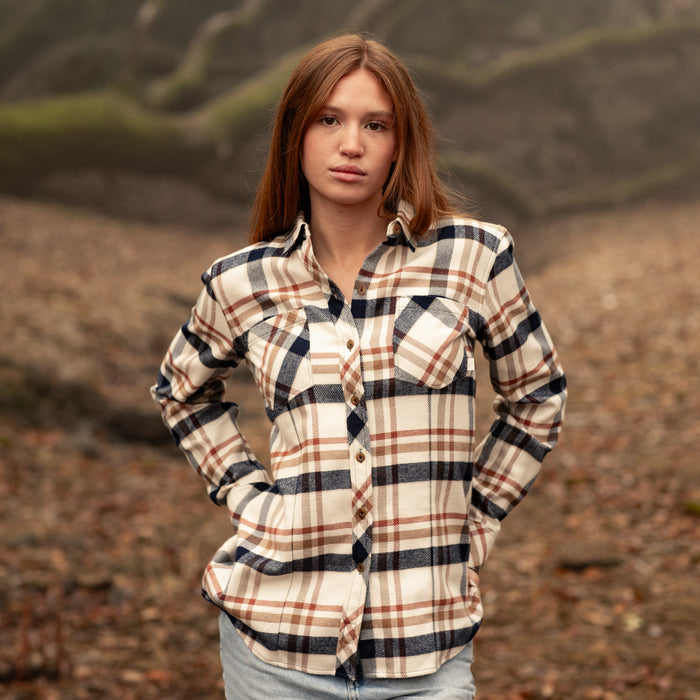 Woman in a Pladra Women's Every Day Elite Flannel Shirt - Whitefish Tan stands outdoors, hands behind her back.