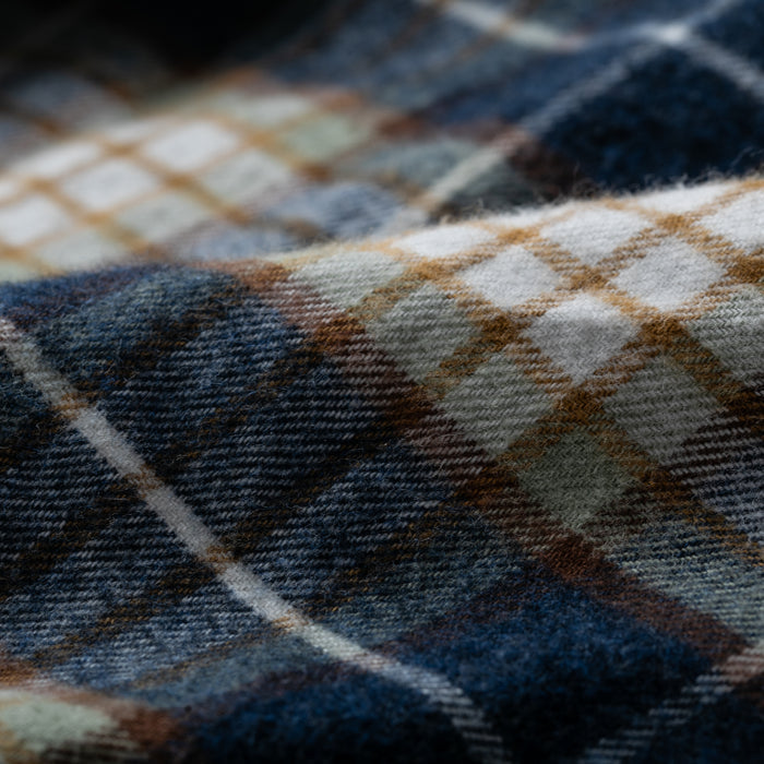 Close-up of the Women's Every Day Flannel Shirt in Banff Blue, showing soft, textured Portuguese cotton flannel with a blue, brown, white, and beige plaid. The slightly rumpled fabric highlights its thickness and cozy warmth.