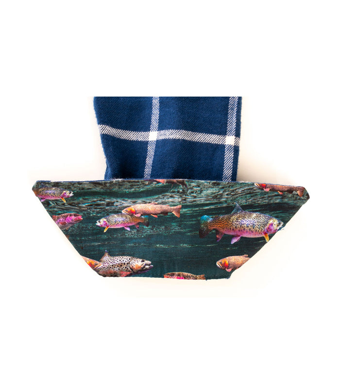 A blue plaid cloth napkin, inspired by the Women's Every Day Flannel Shirt- Billings Blue, is partly wrapped in a fabric ring adorned with colorful fish swimming in water.