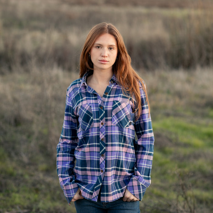 Young woman wears Pladra Women's Every Day Flannel Shirt in Blackberry Purple, standing outdoors in a grassy field.