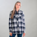 A woman in Pladra's Women's Every Day Flannel Shirt - Butte Blue and blue jeans stands with her long hair loose.