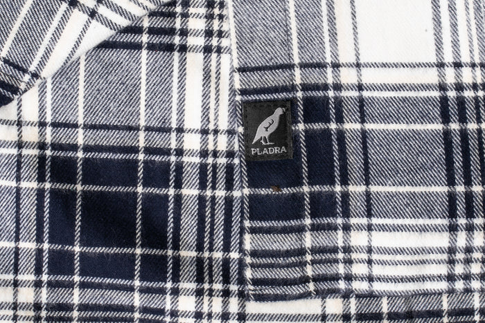 Close-up of Pladra Women's Every Day Flannel Shirt in Butte Blue, featuring the brand's bird logo tag.