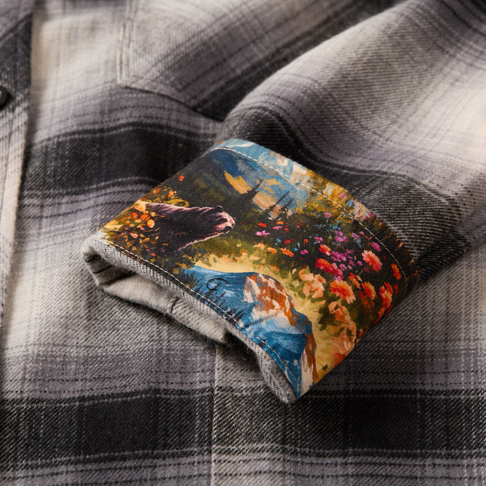A close-up of the Women's Every Day Flannel Shirt in Sterling Grey Heather, showing its turned-up cuff and a vibrant cotton flannel inner lining with floral, greenery, and river designs.
