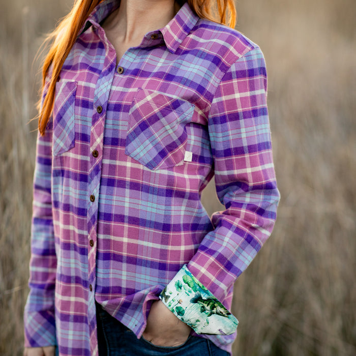 Woman with long red hair wears Pladra's Women's Every Day Flannel Shirt in Wildflower Pink, outdoors with hand in pocket.