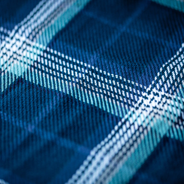 Close-up of Women's Fireside Flannel in Laguna Blue, featuring a blue and white plaid pattern on soft organic cotton with detailed woven texture and intersecting lines in shades of blue, white, and teal.